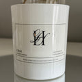 White candle with a label on a reflective surface