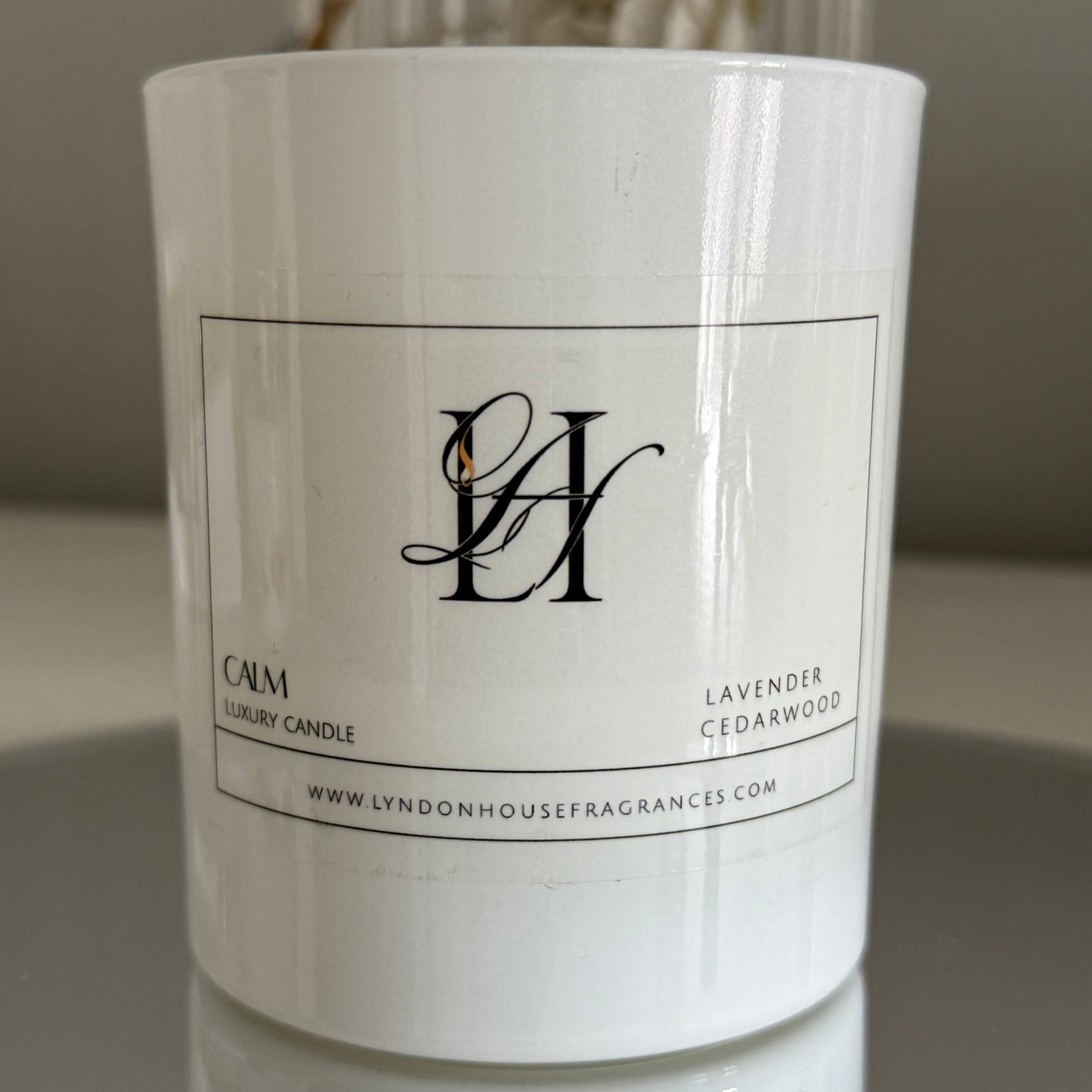 White candle with a label on a reflective surface
