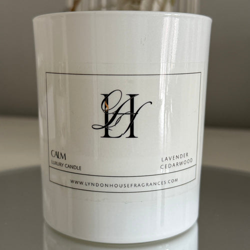 White candle with a label on a reflective surface