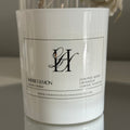 White candle with a label on a reflective surface