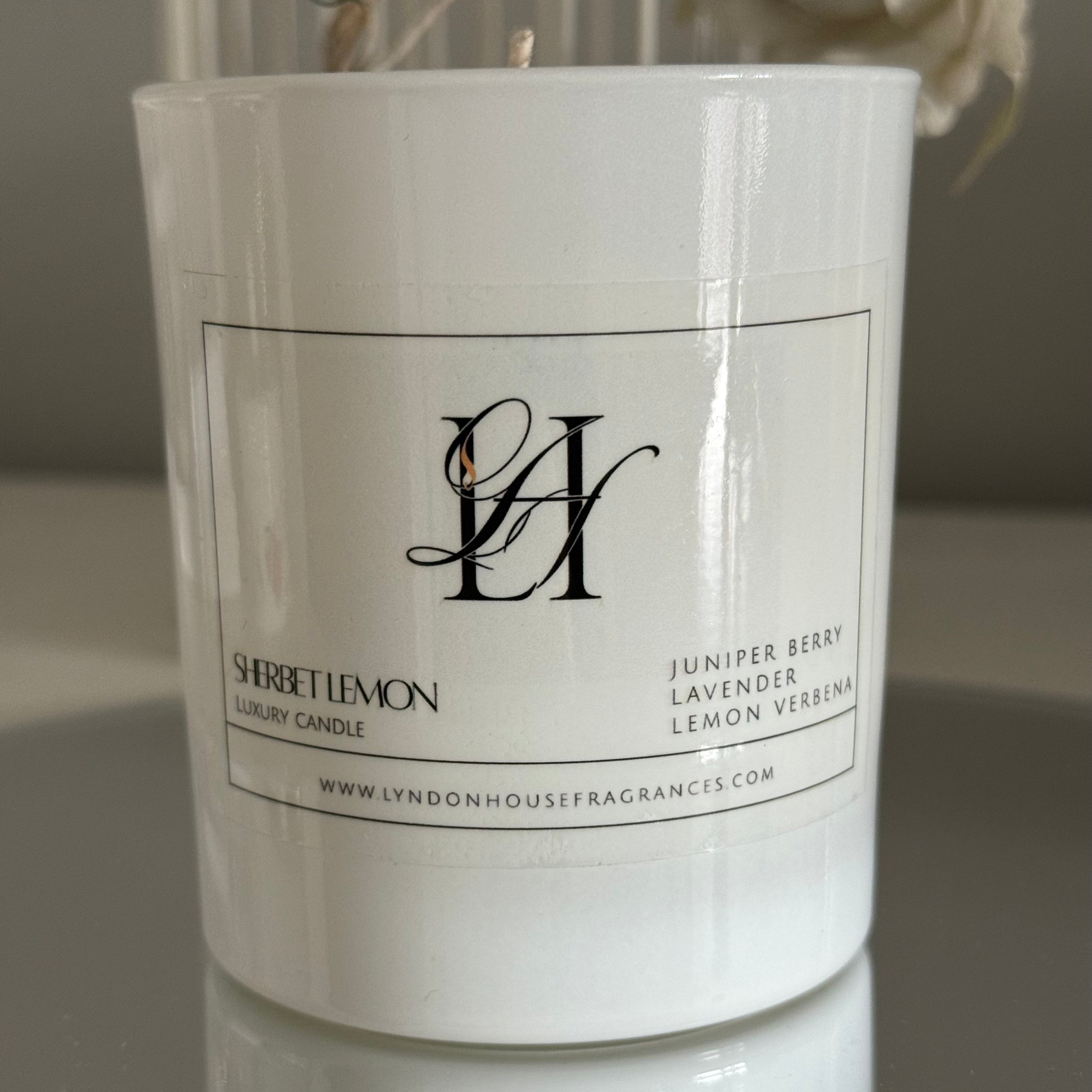 White candle with a label on a reflective surface