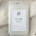 A wax melt package labeled 'VELVET BERRY WAX-MELT AROMA BAR' placed on a textured cream fabric background with tassels.